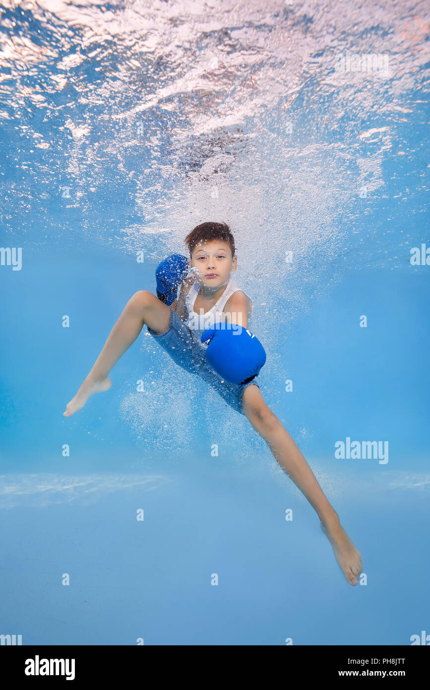 A boy in boxing gloves posing underwater in the pool Stock Photo