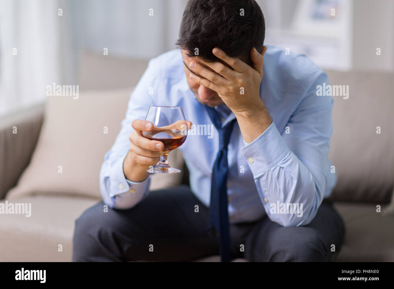 drunk man with glass of alcohol at home Stock Photo