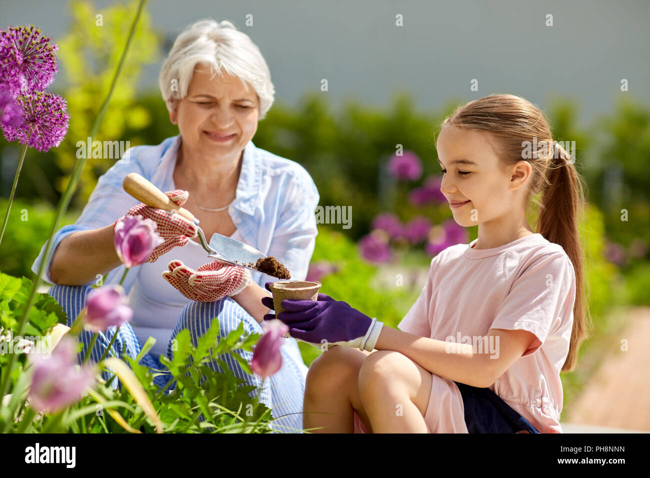 grandmother and girl planting flowers at garden Stock Photo