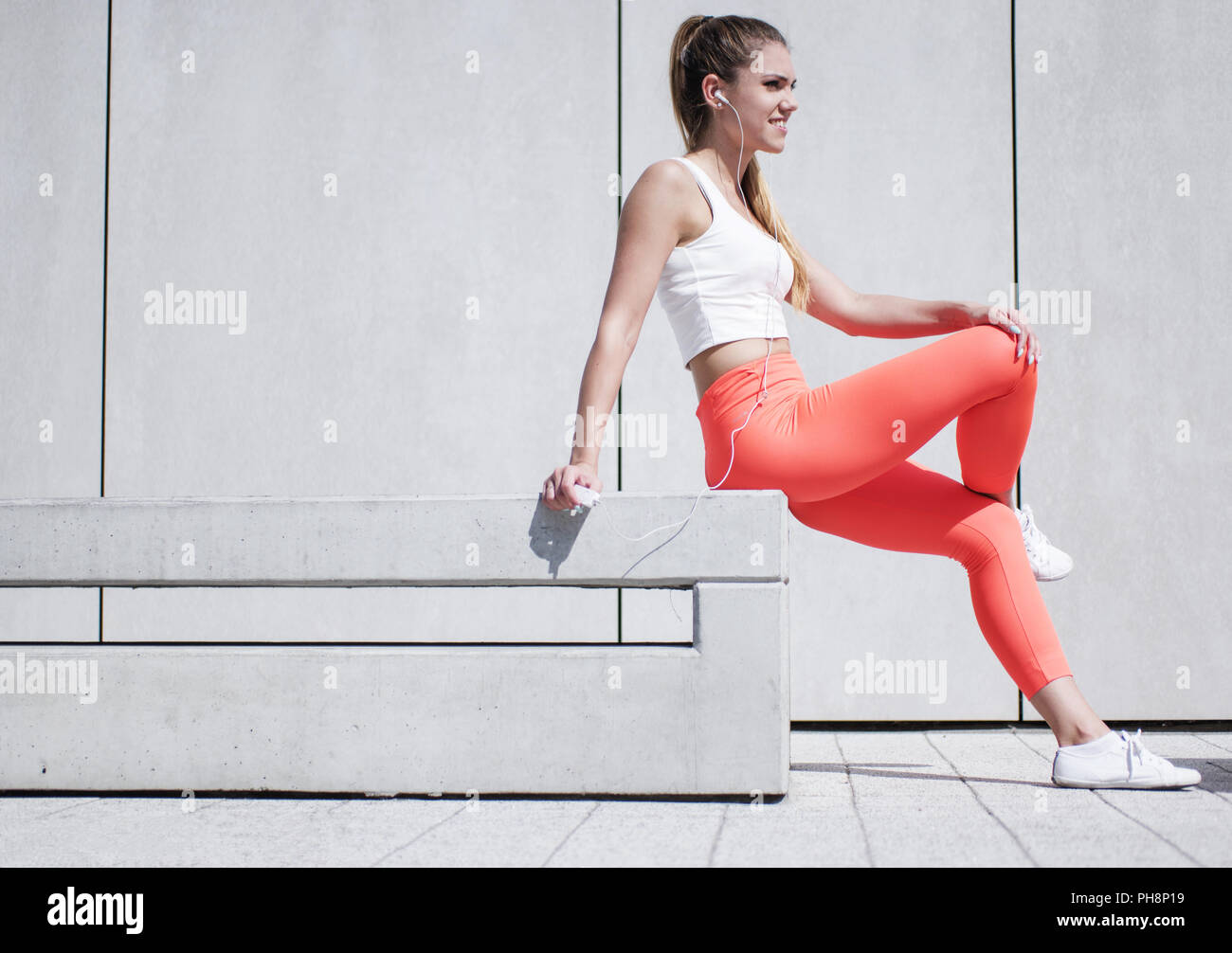 Pretty Woman in Sports Attire Sitting on the Bench Stock Photo