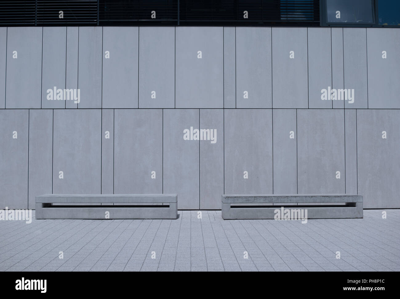 Two Similar Benches Against White Building Wall Stock Photo