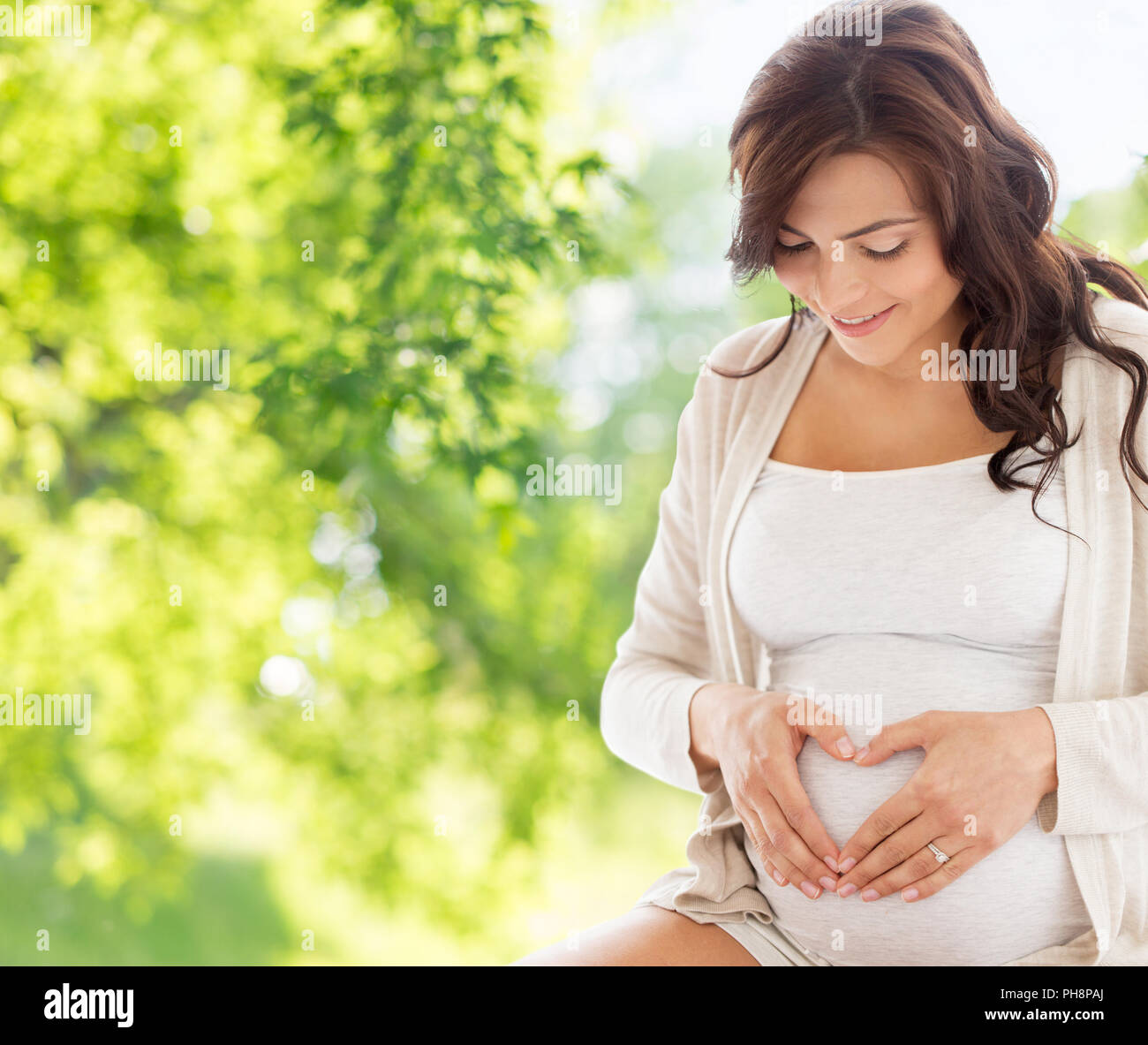 happy pregnant woman making heart gesture Stock Photo