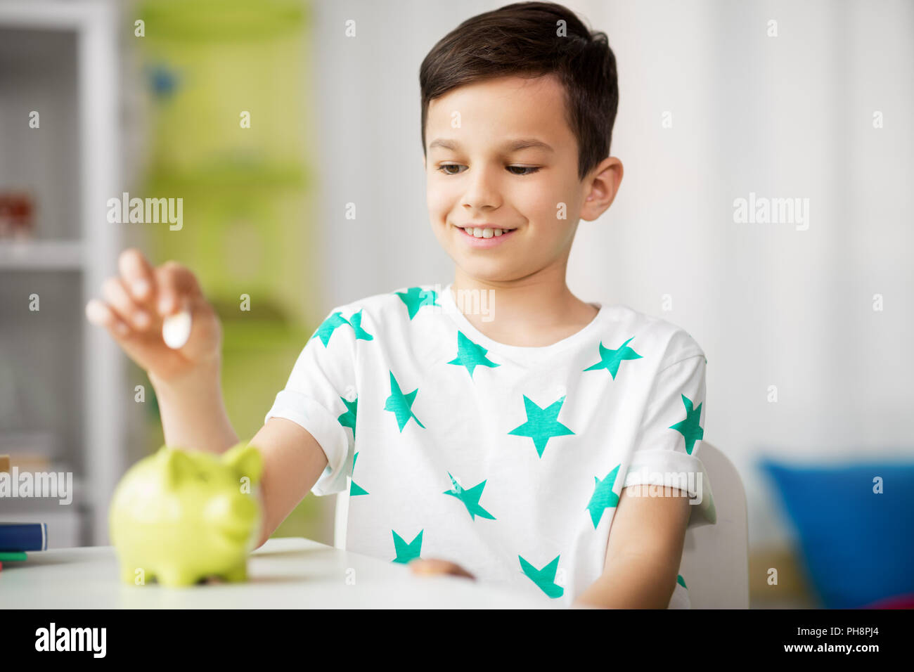 little boy putting coin into piggy bank at home Stock Photo - Alamy