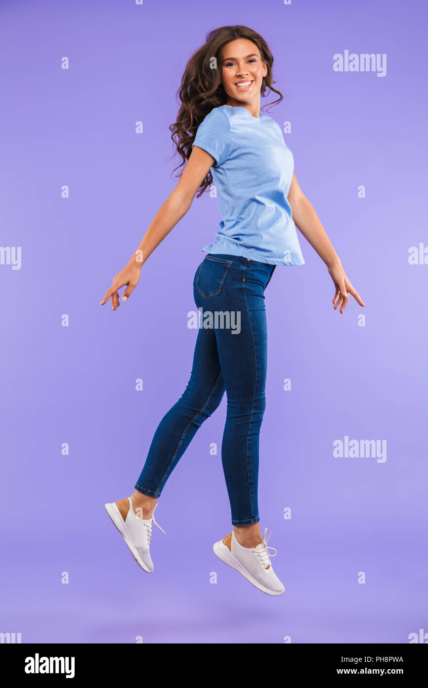 Full length portrait of a cheerful young woman jumping isolated over ...