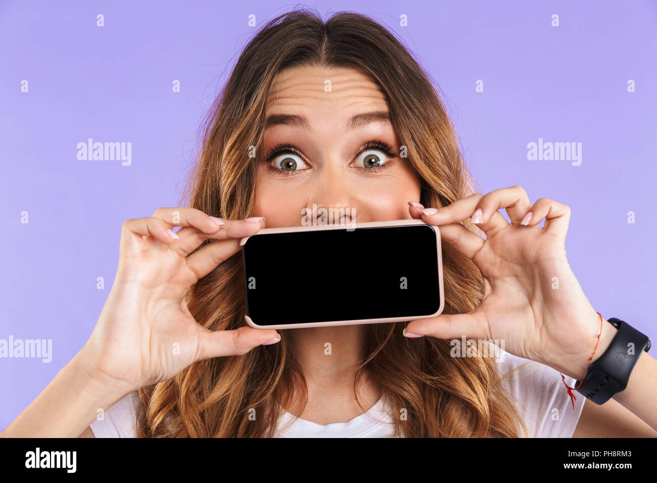 Image of emotional woman isolated over purple wall background showing display of mobile phone. Stock Photo