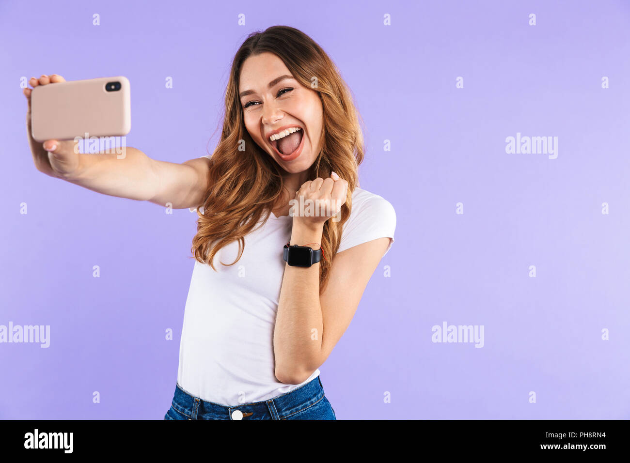 Portrait of a cheerful young girl taking a selfie isolated over violet ...