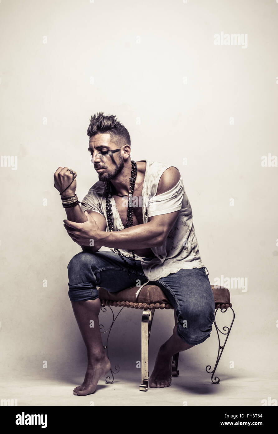 Poor Strong Young Man on a Chair Clenching Fist Stock Photo
