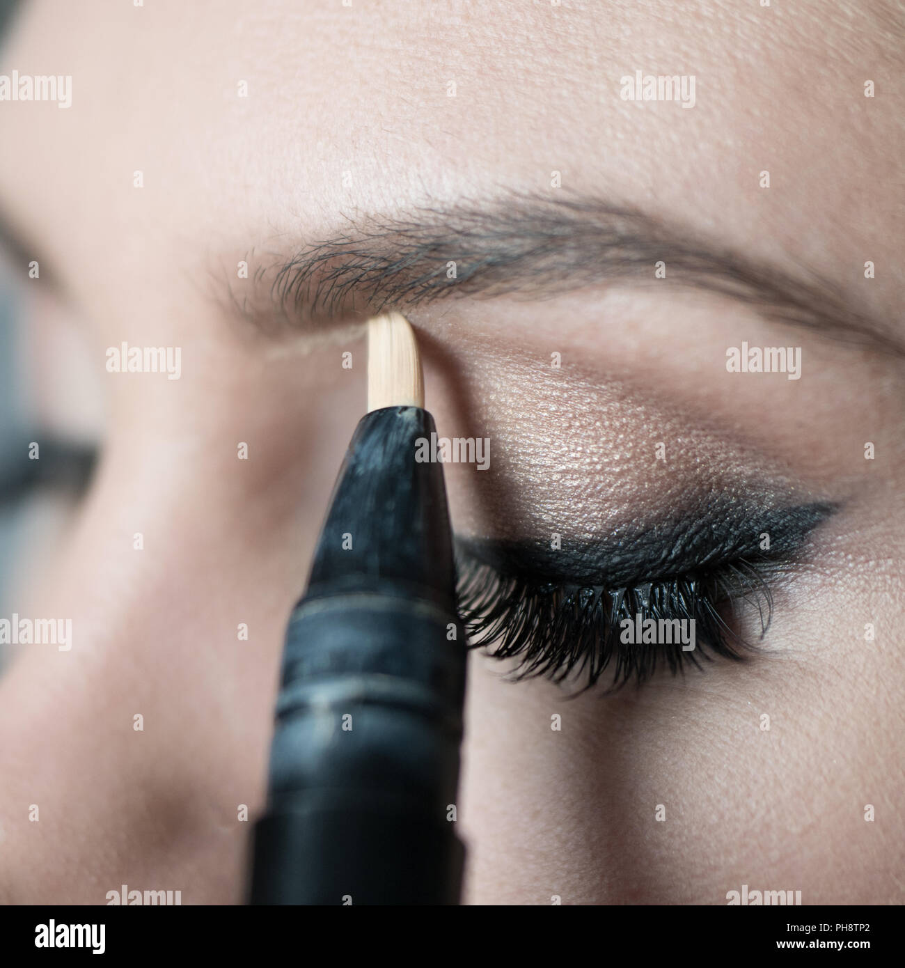 Close Up of Woman Applying Make Up Along Brow Line Stock Photo