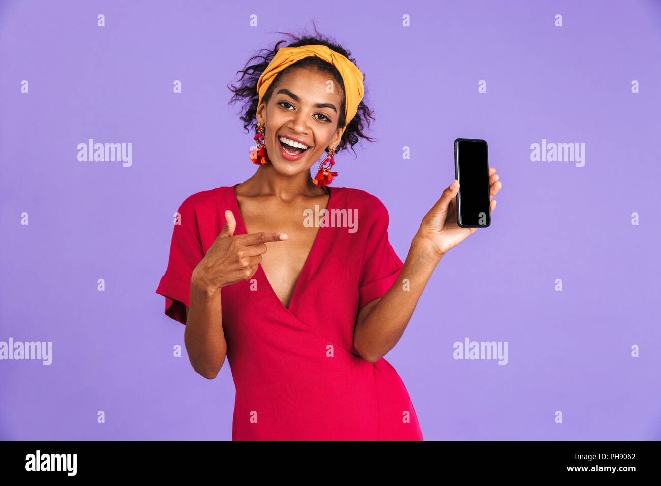 Happy african woman in dress showing blank smartphone screen and ...