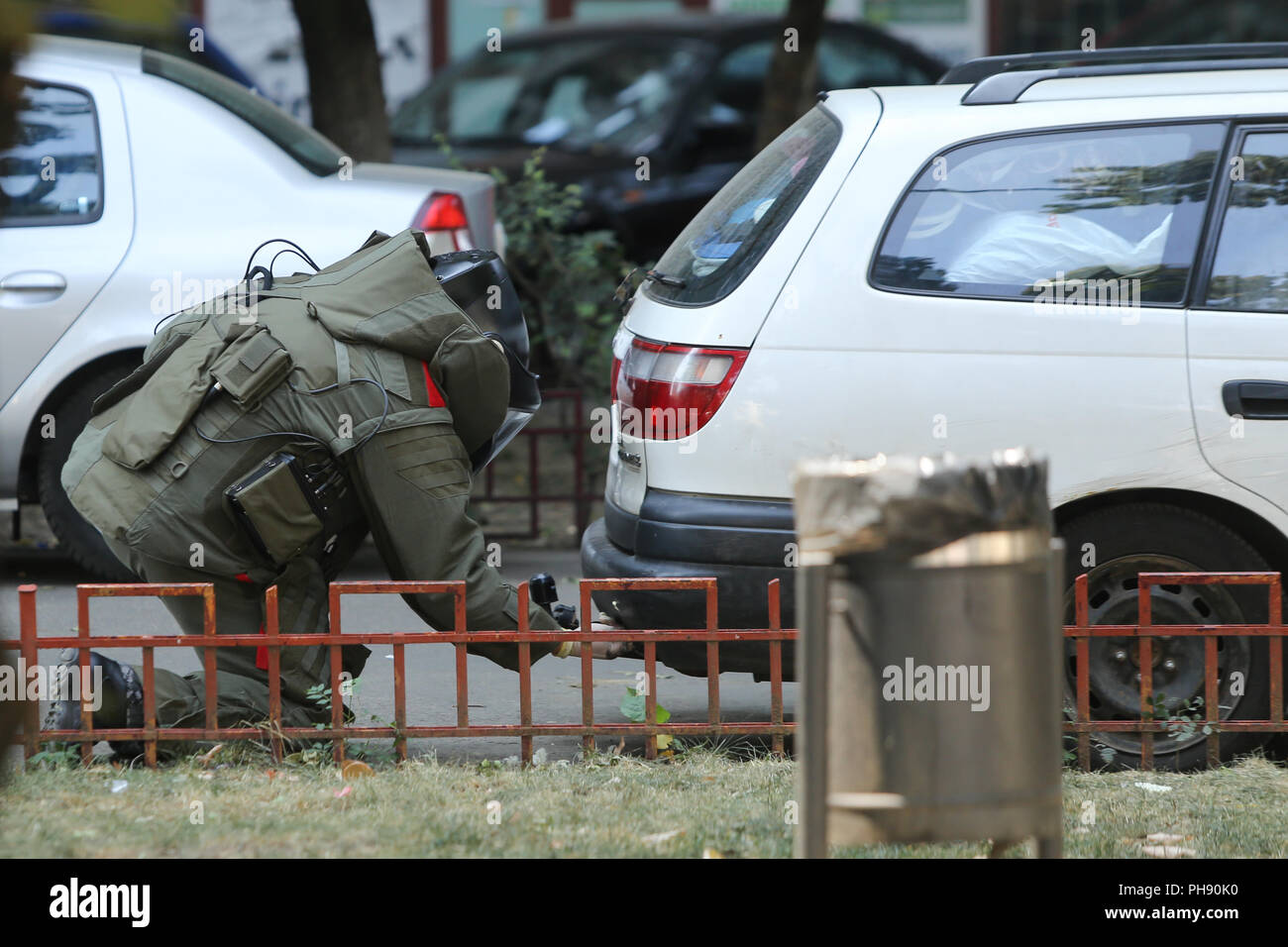 BUCHAREST, ROMANIA - August 31, 2018: Bomb Disposal Expert in Bomb suit for Explosive ordnance disposal (EOD) is verifying a suspect car on a street i Stock Photo