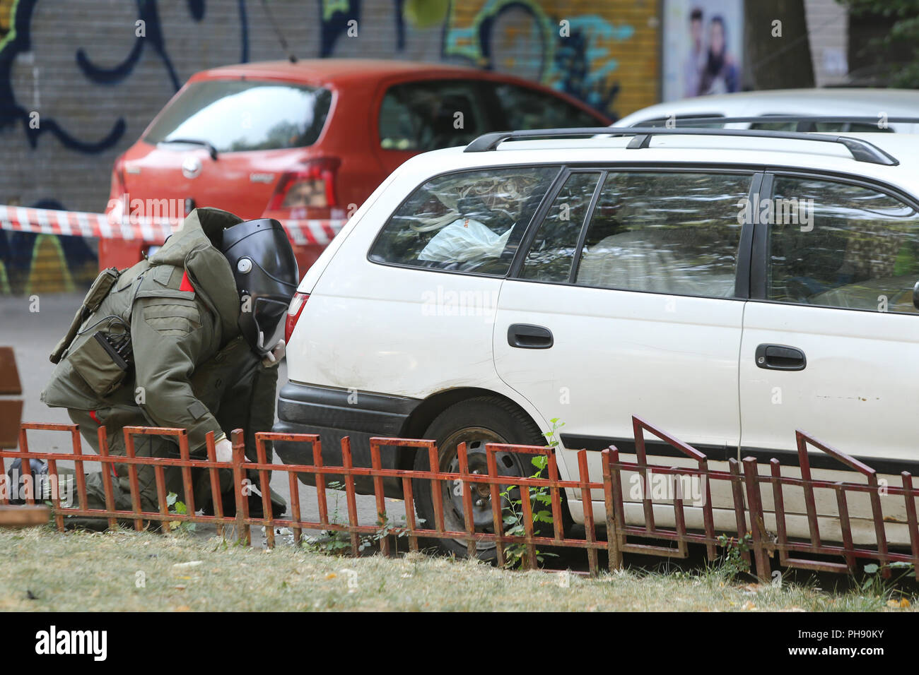 BUCHAREST, ROMANIA - August 31, 2018: Bomb Disposal Expert in Bomb suit for Explosive ordnance disposal (EOD) is verifying a suspect car on a street i Stock Photo