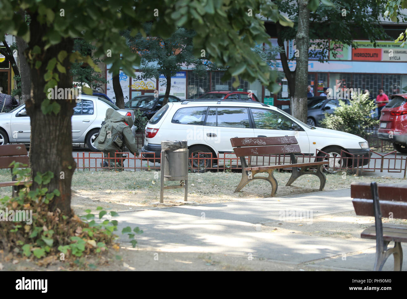BUCHAREST, ROMANIA - August 31, 2018: Bomb Disposal Expert in Bomb suit for Explosive ordnance disposal (EOD) is verifying a suspect car on a street i Stock Photo