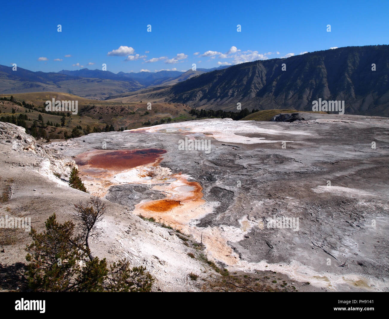 Barren field with hills and blue sky in background Stock Photo