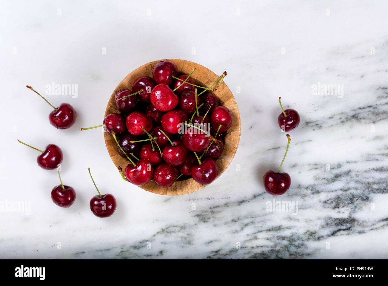 Fresh bowl of sweet red cherries on marble stone countertop Stock Photo