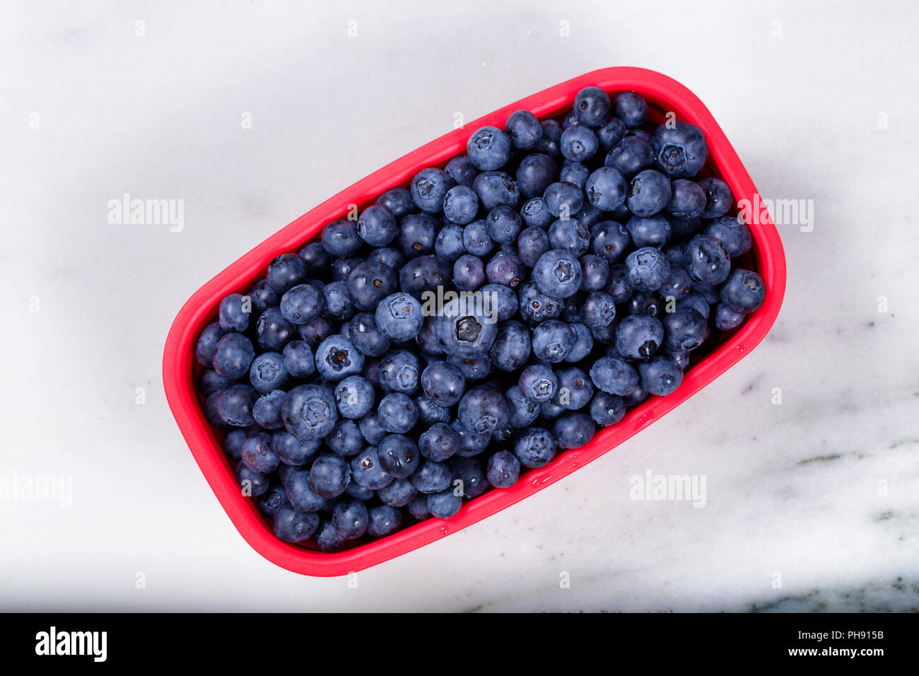 Fresh basket of ripe blueberries on marble stone countertop Stock Photo