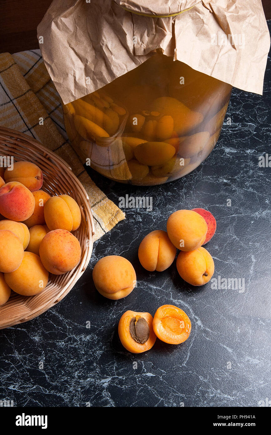 Ripe organic apricots harvested at summer time and big glass jar with