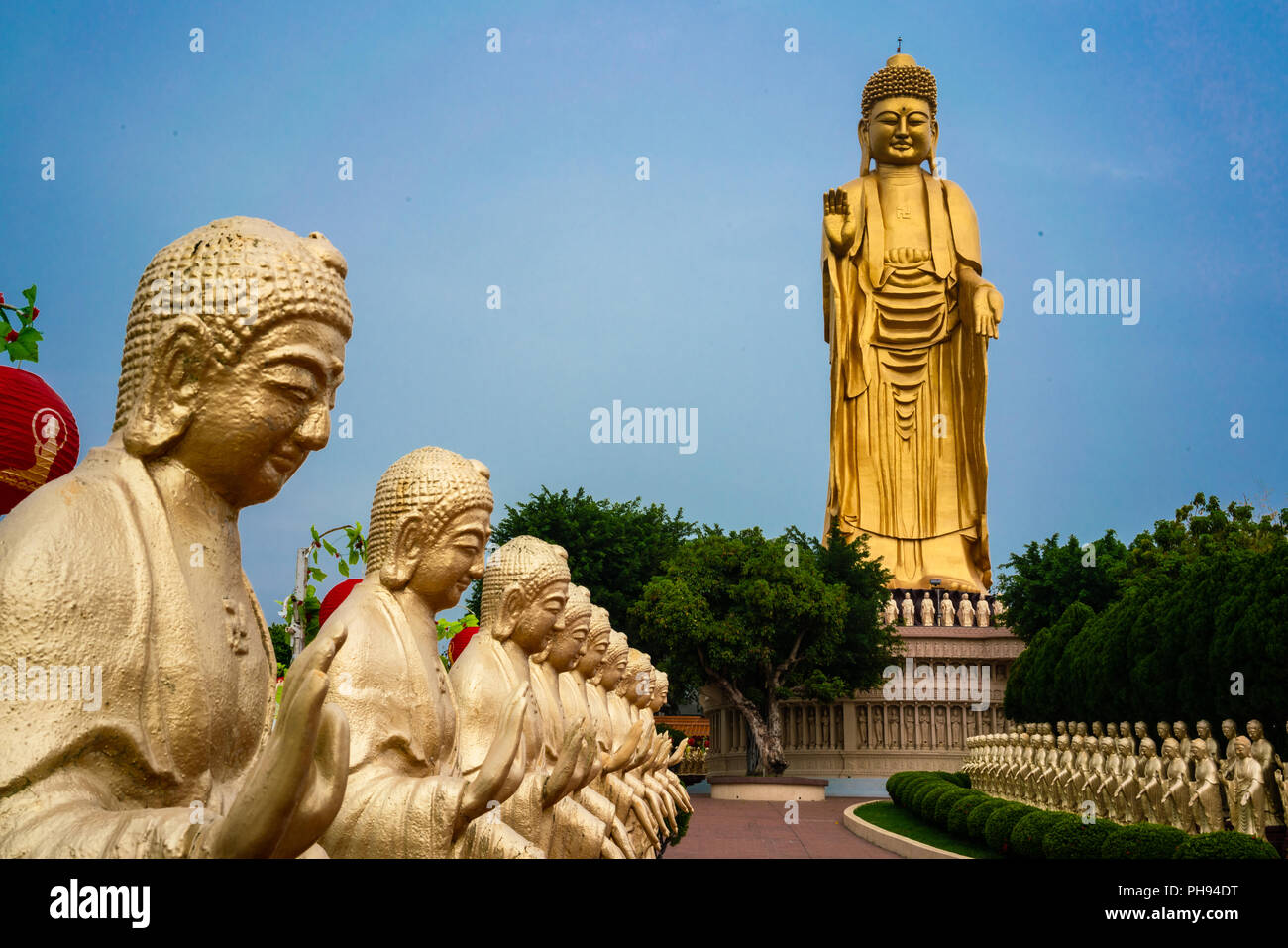 Close-up view of golden Buddha statue and giant Great Buddha statue in background at Fo Guang Shan Monastery in Kaohsiung Taiwan Stock Photo
