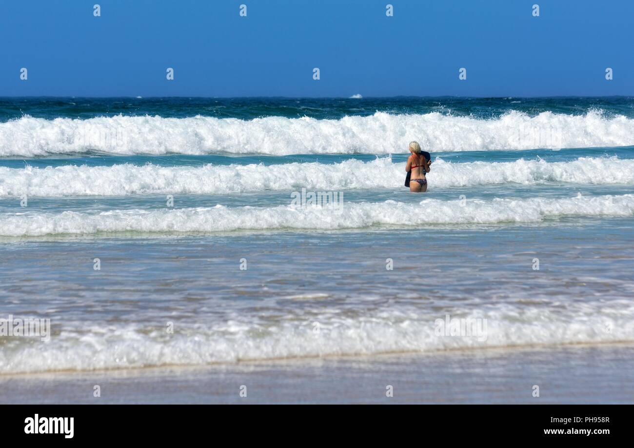 Blond woman walking into the sea with a body board,Riviere Towans beach