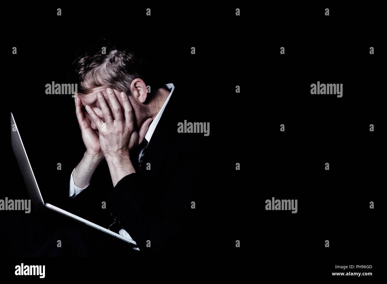 Heavily stressed man at work in the darkness Stock Photo