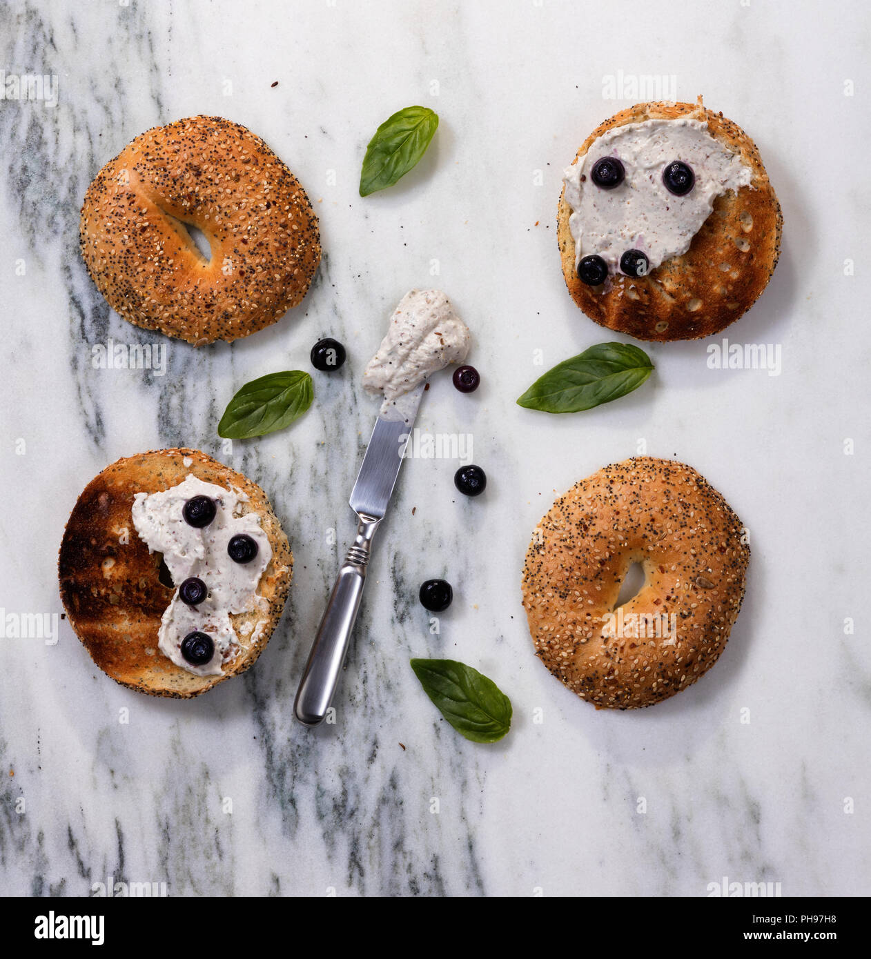 Toasted bagels with cream cheese and herbs on marble countertop Stock