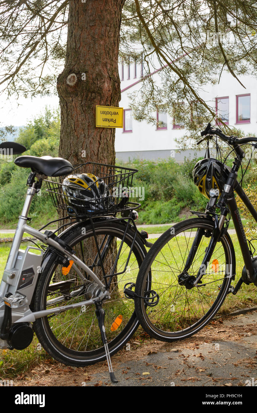 Precious bicycles and helmets are parked in a park ban Stock Photo