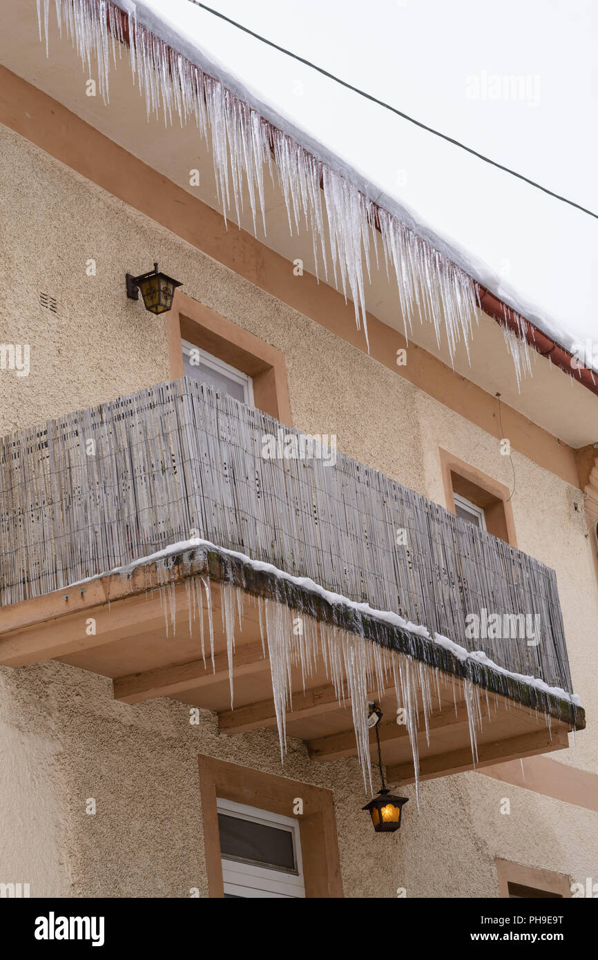 Large icicles hanging idyllically from several floors of a house Stock Photo