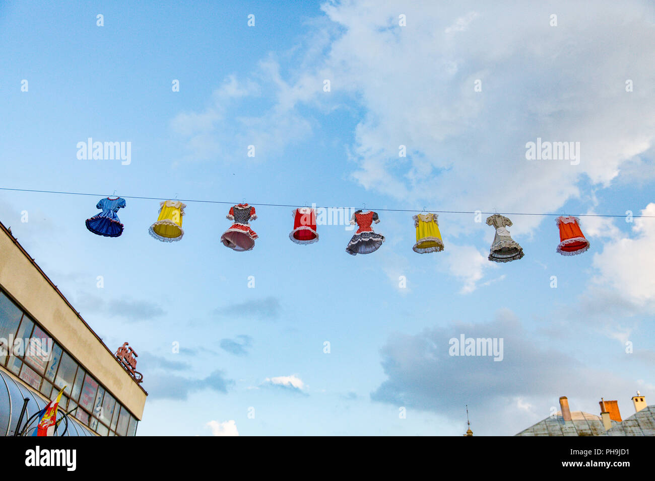 A display of colorful dresses hanging above the streets of Krosno town in Poland during the Carpathian Climates Festival. Stock Photo