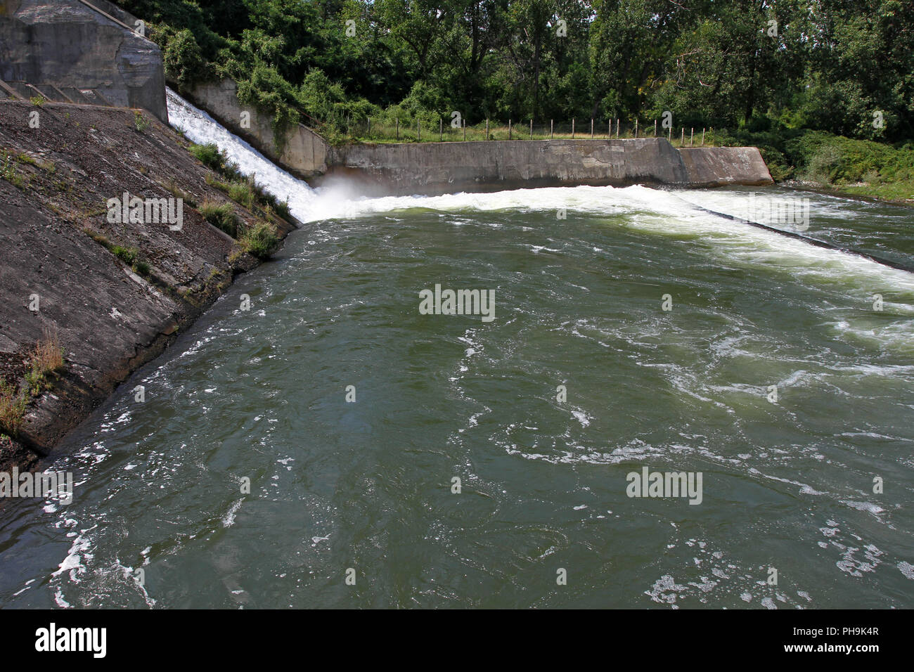 Dam wall and overflow of Iskar Dam. Water flowing over a dam wall. Mist ...