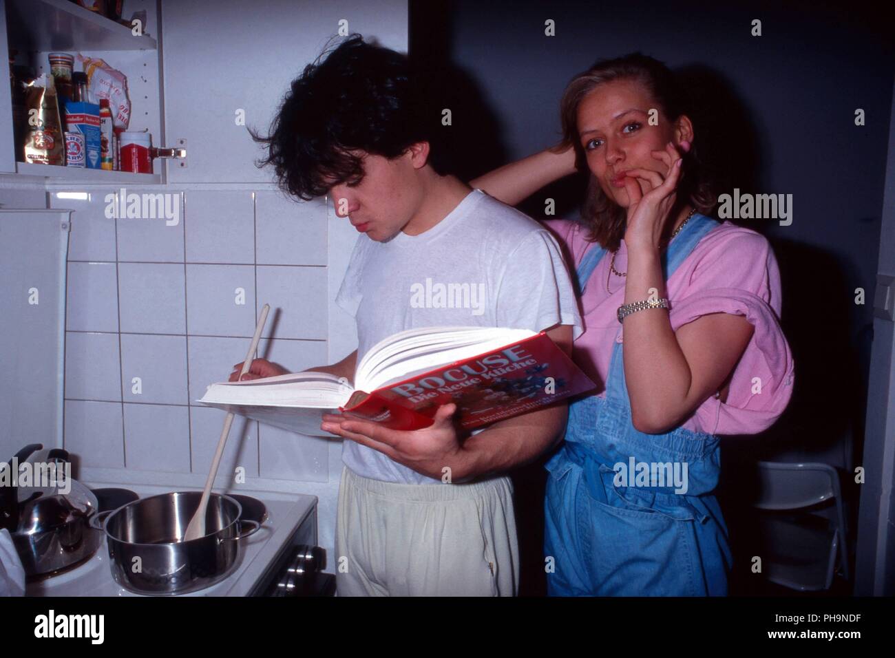Sänger Nino de Angelo studiert mit Freundin Judith Coersmeier ein Kochbuch von Paul Bocuse in einer Homestory Fotoreportage in Köln, Deutschland 1983. Stock Photo