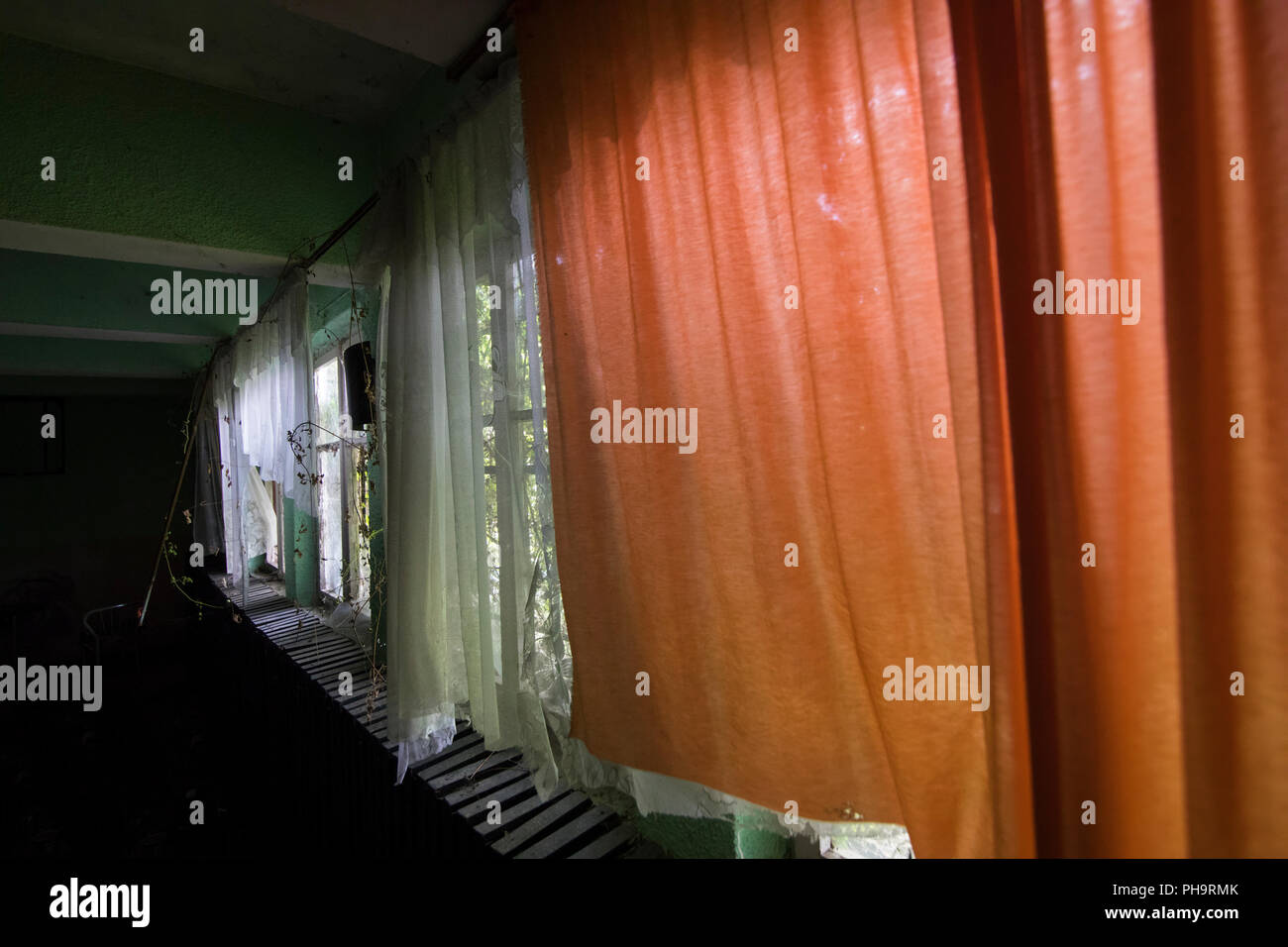 Interior abandoned house in Bulgaria with red curtains and lace curtain Stock Photo