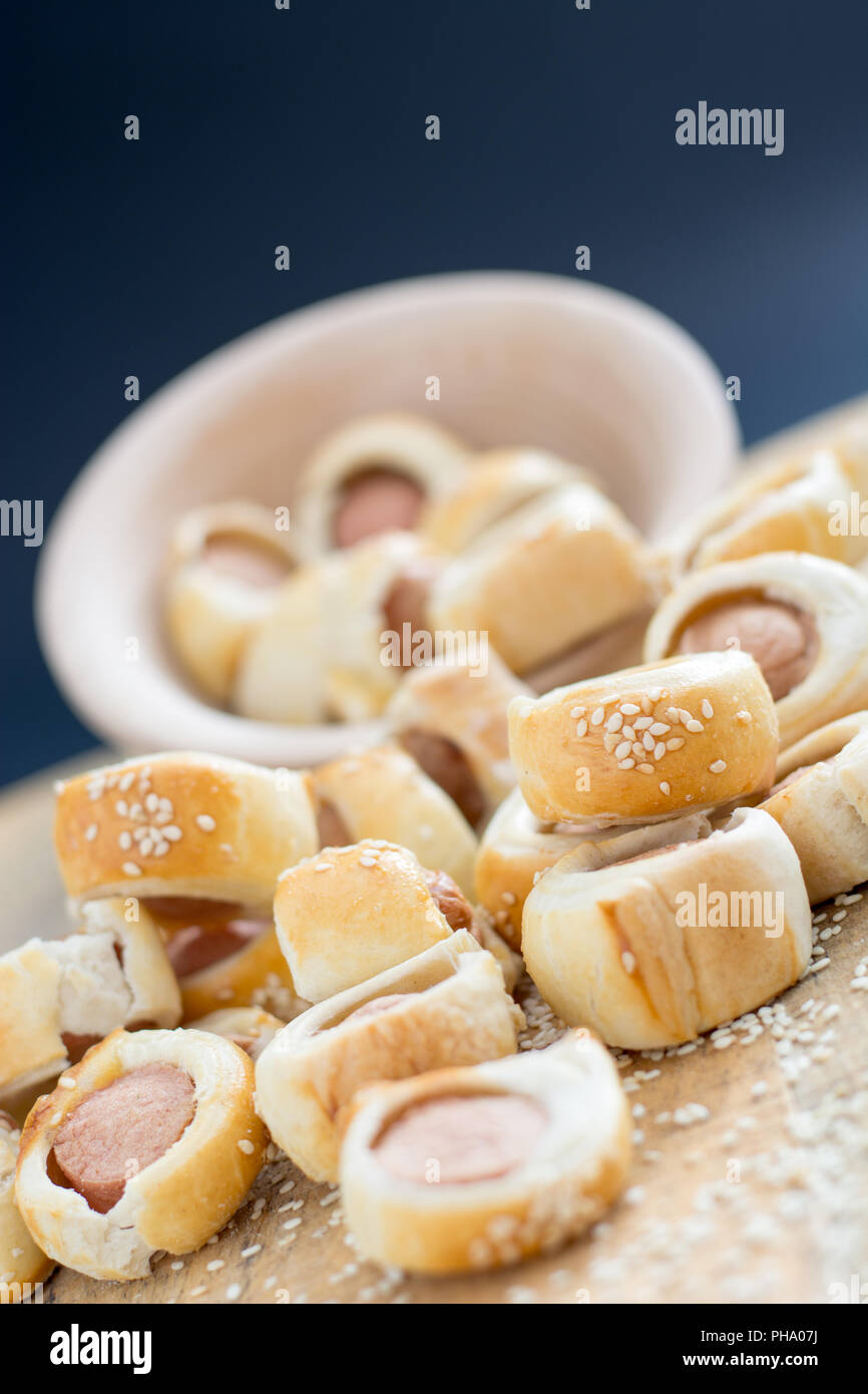 Sausages rolled in croissant dough baked cooling on metal rack. Stock Photo