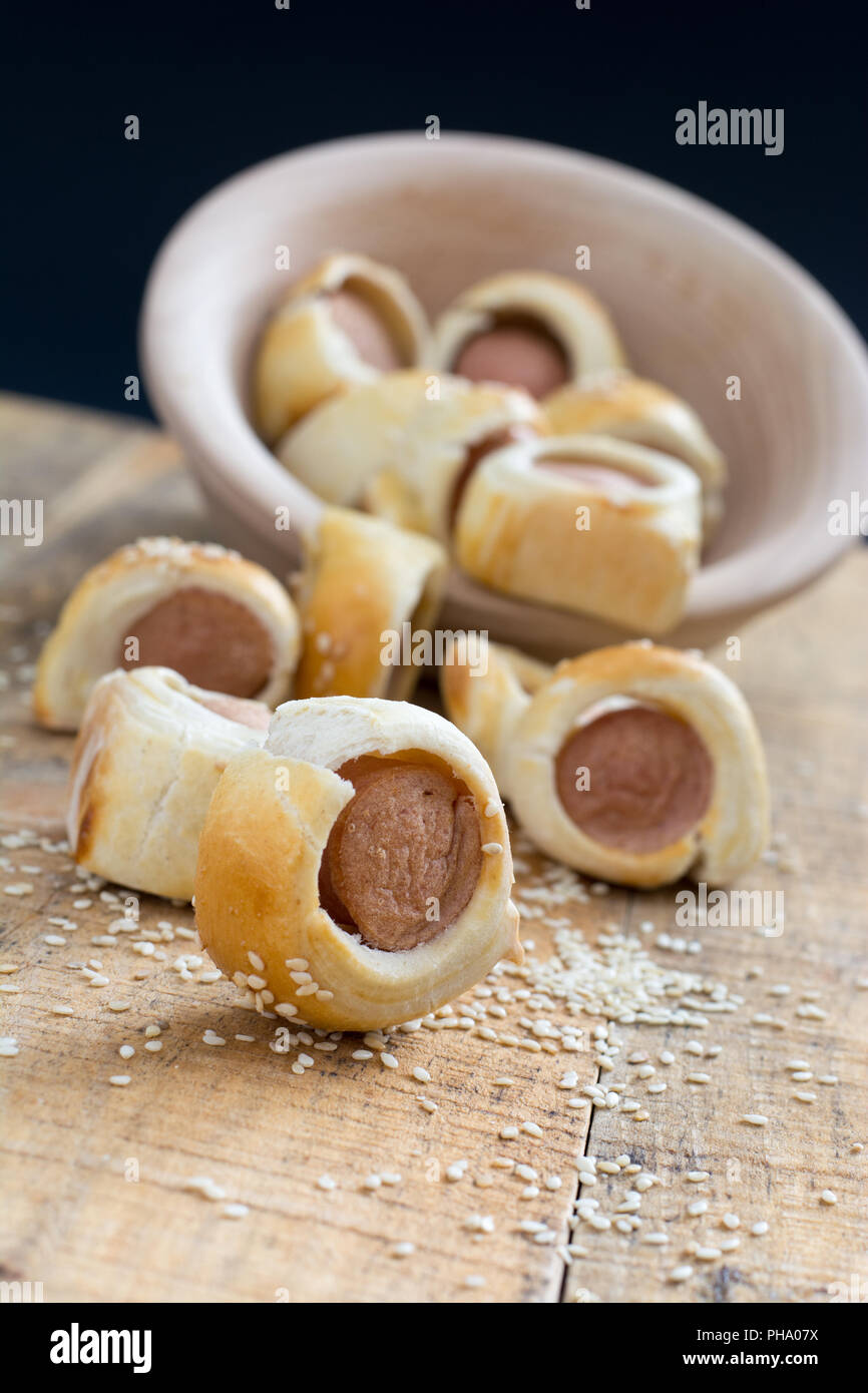 Sausages rolled in croissant dough baked cooling on metal rack. Stock Photo