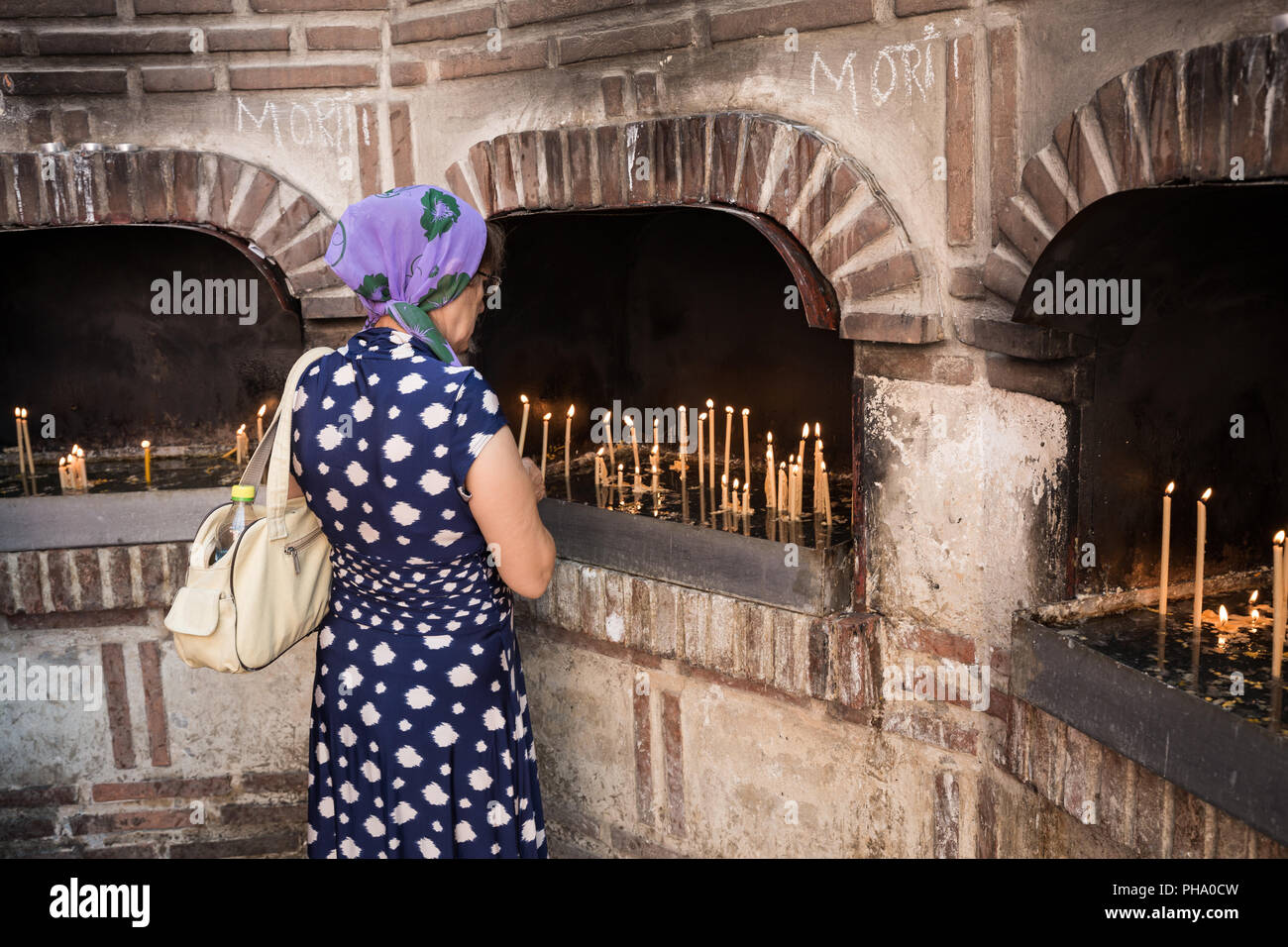 A female worshiper lights a candle outside the Biserica Sfantul Anton in Bucharest, Romania, Europe Stock Photo