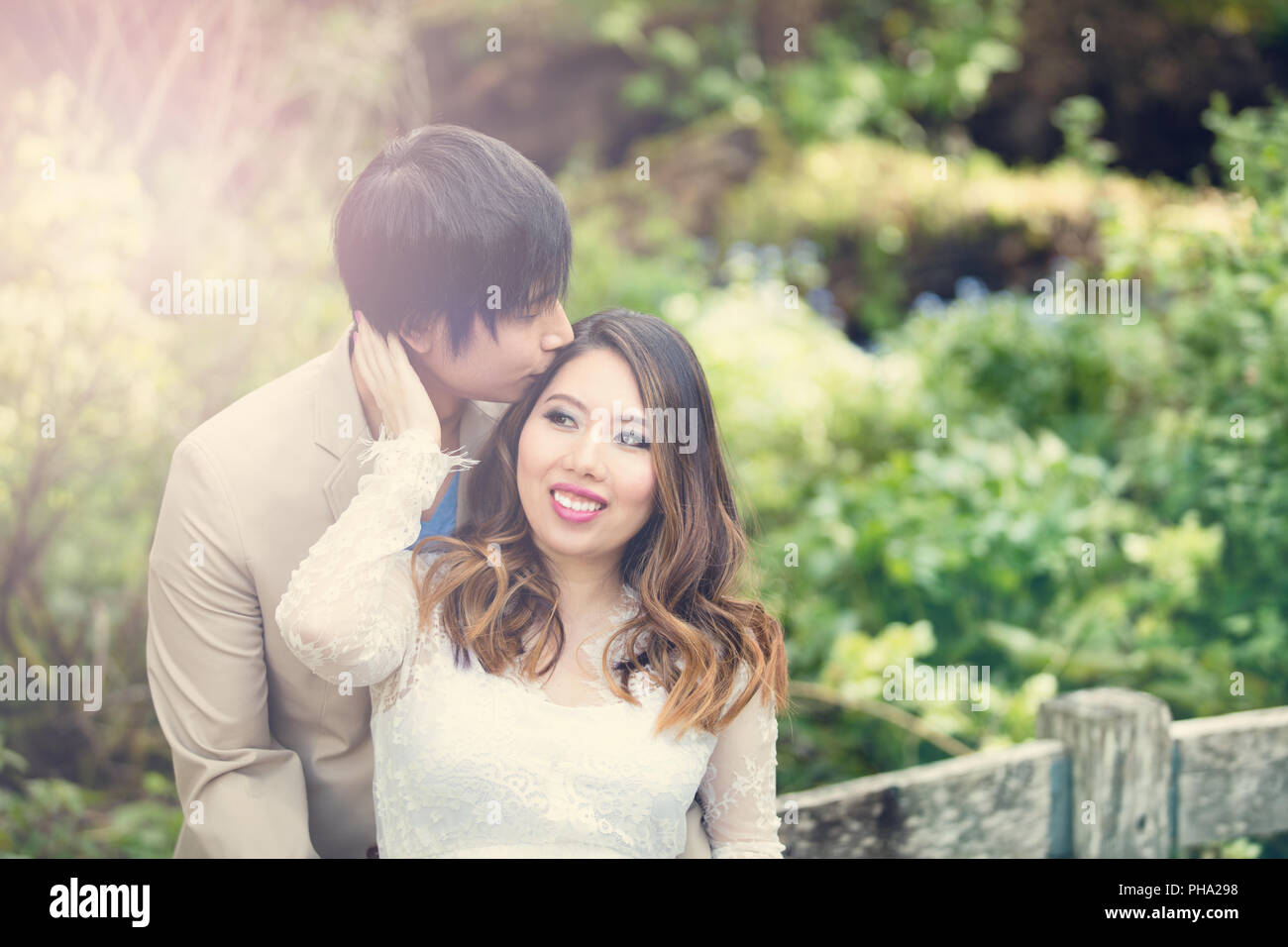 Expecting mom receiving kiss from her husband while outdoors Stock Photo