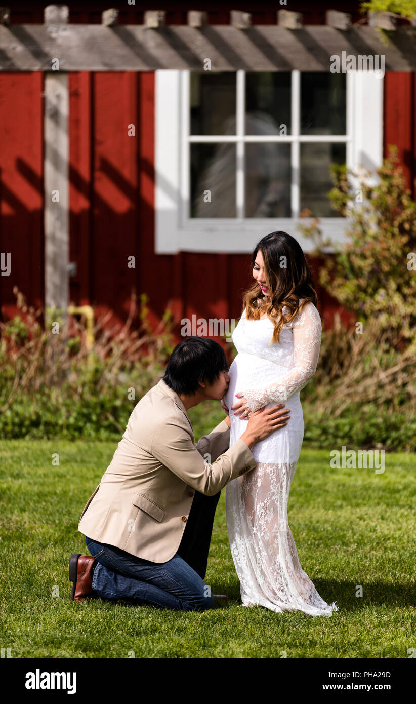 Future baby receiving kiss from dad with mom watching Stock Photo