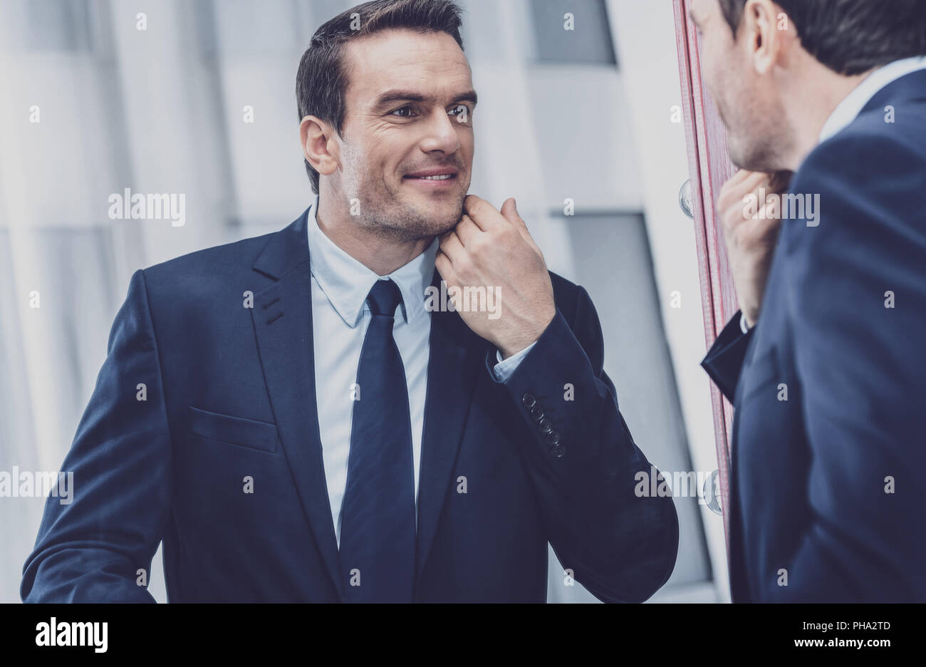 Charismatic entrepreneur looking at himself in the mirror Stock Photo