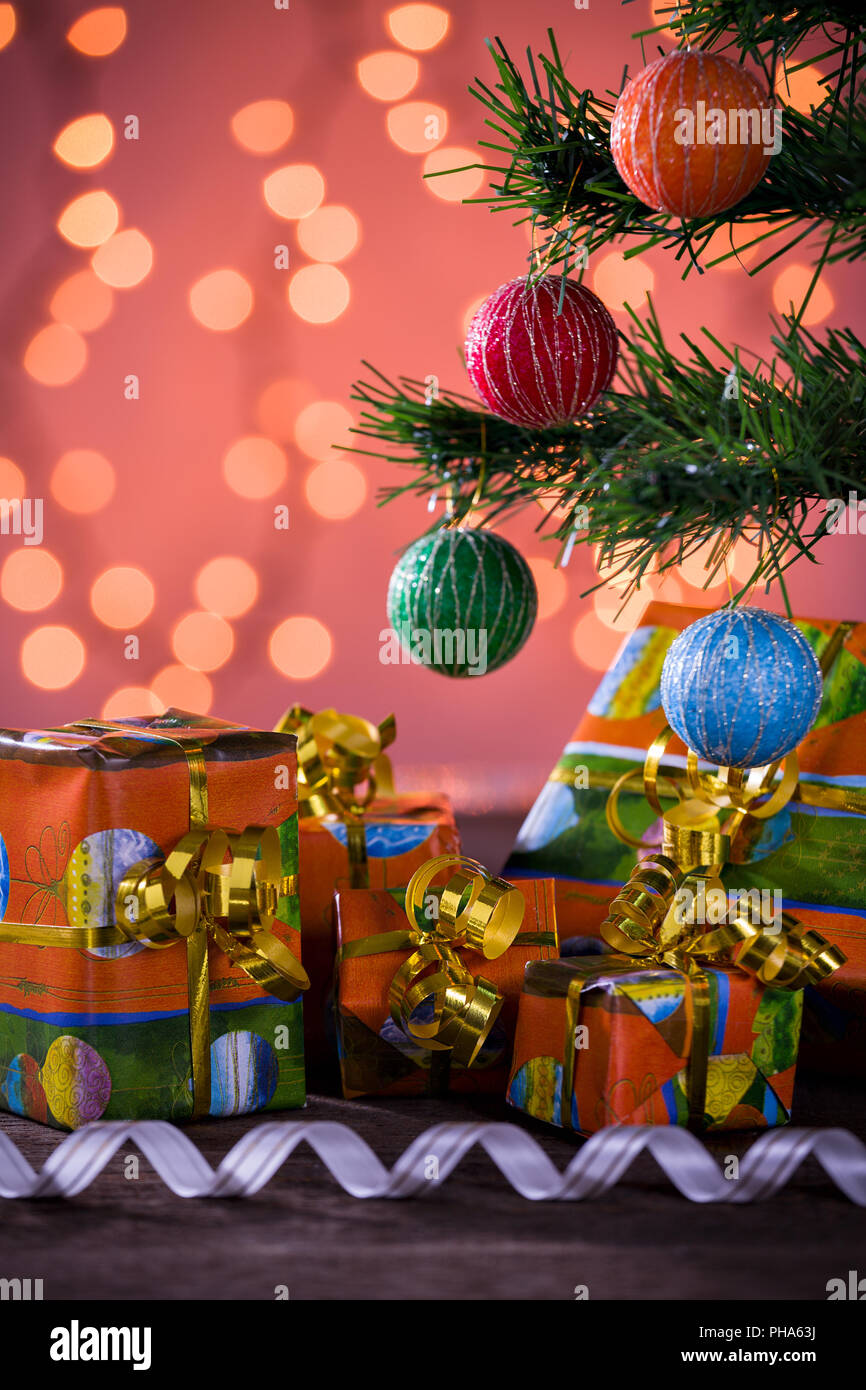 Christmas gifts with blurred lights and ribbon under the tree Stock Photo