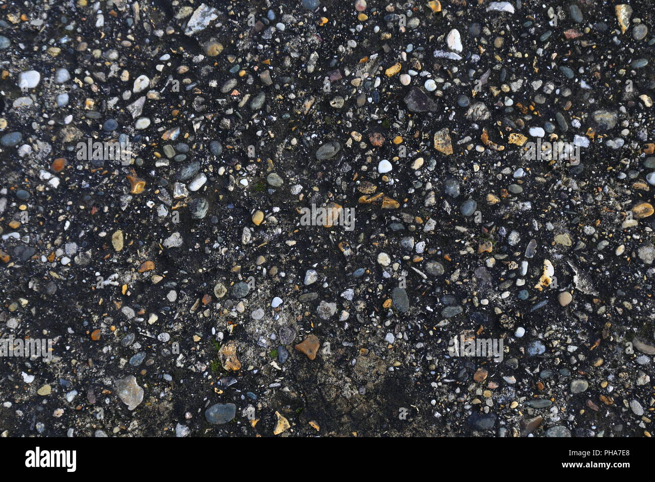 Background motif: small pebbles in dark soil Stock Photo