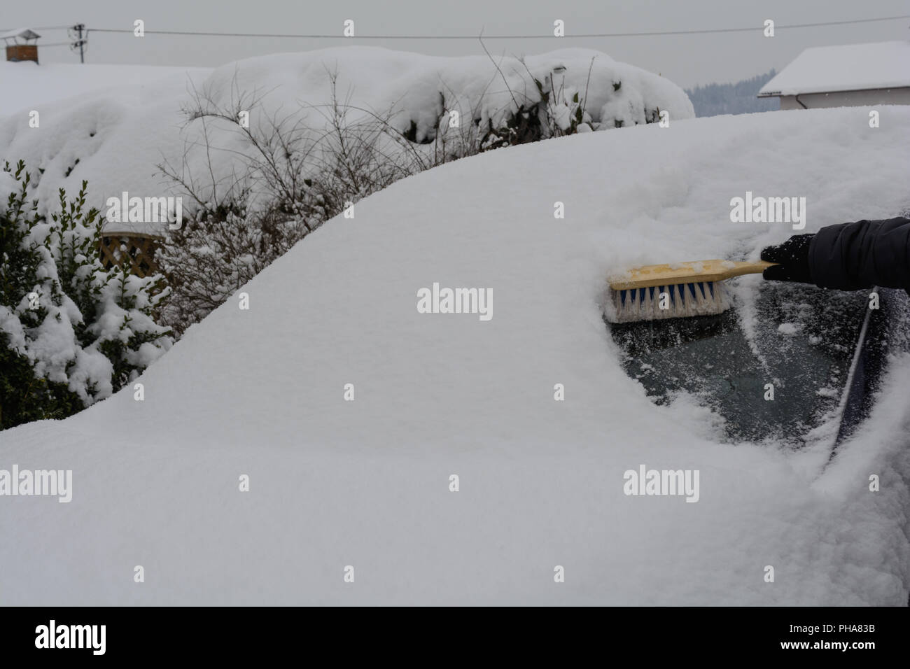 Deep snowy car is freed from snow with whisk Stock Photo