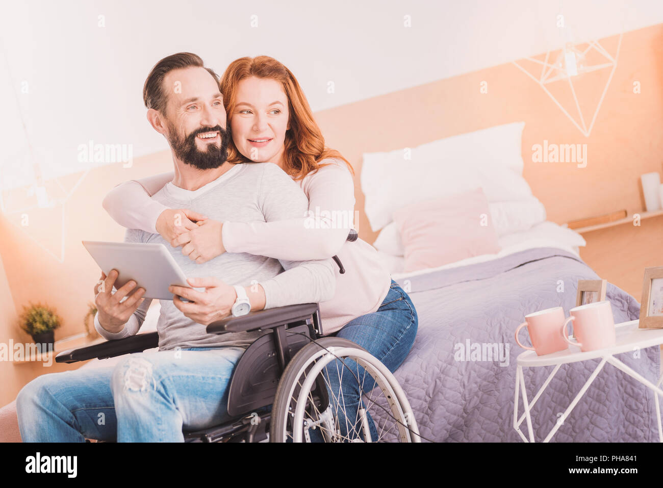 Cheerful wheelchaired man using a tablet with his wife Stock Photo