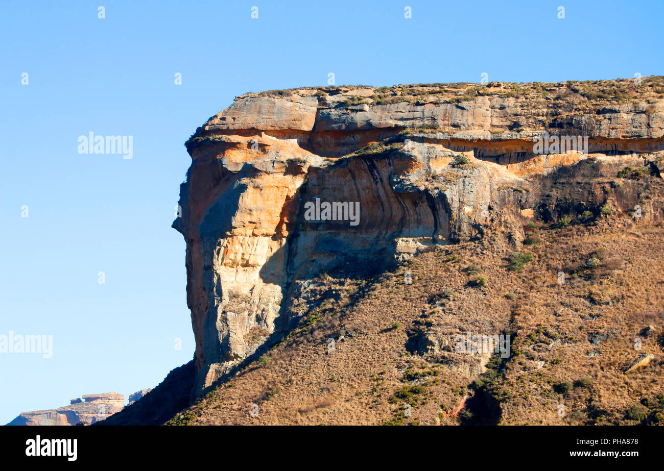 A rocky sandstone mountain jutting out on a blue sky background Stock Photo