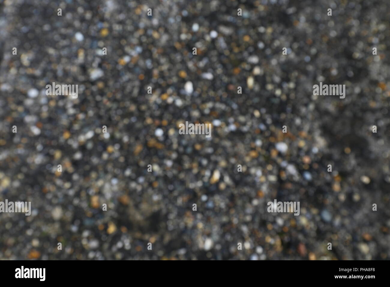 Blurred background motif: small pebbles in dark soil Stock Photo