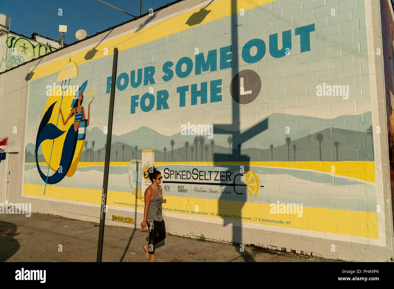 SpikedSeltzer billboard in the Williamsburg neighborhood in Brooklyn opposite a free bicycle branding event for the alcoholic beverage brand, SpikedSeltzer, on Tuesday, August 28, 2018. The Metropolitan Transportation Authority will be shutting down the 'L' train for 15 months, the lifeline in and out of Williamsburg, in April 2019 for Hurricane Sandy related repairs. The giveaway of bicycles is to help ease the transportation pain of the neighborhood's residents, as well as a brand promotion called 'Pour Some Out For The L'  geared toward millennials. SpikedSeltzer is a brand of Anheuser-Busc Stock Photo