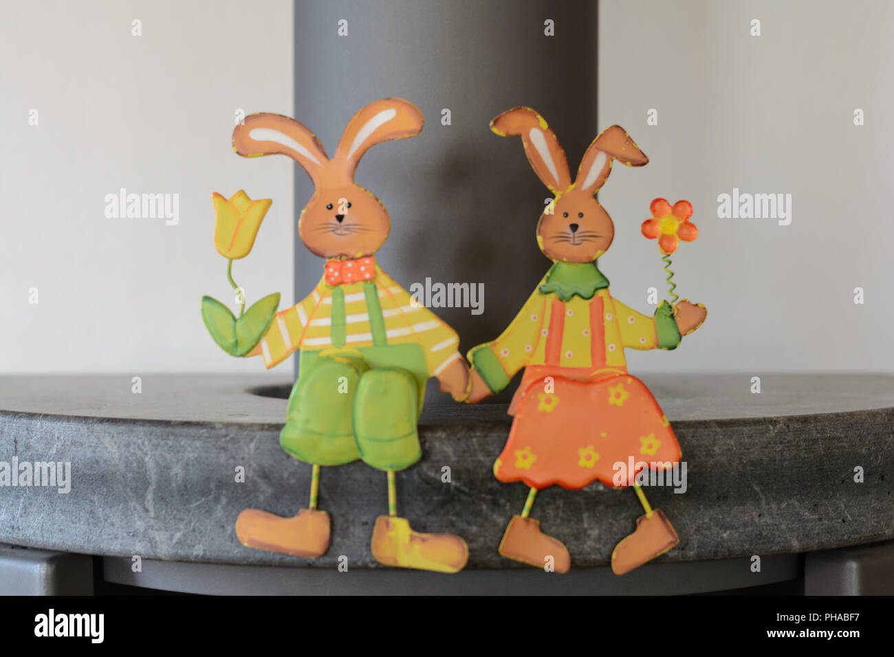 Friendly Easter bunnies hold flowers and sit on stove Stock Photo