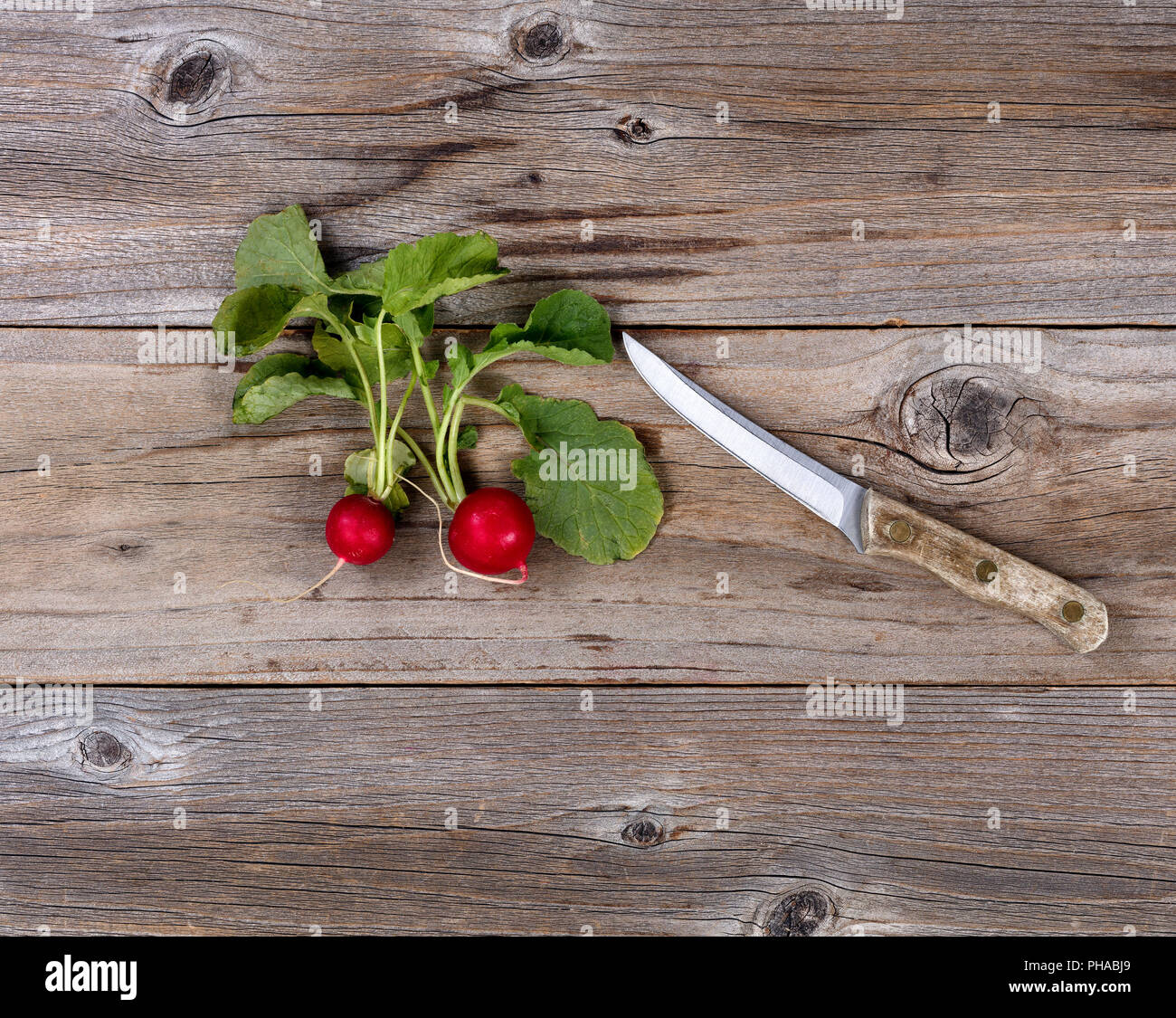 Fresh radish and paring knife on rustic wood Stock Photo
