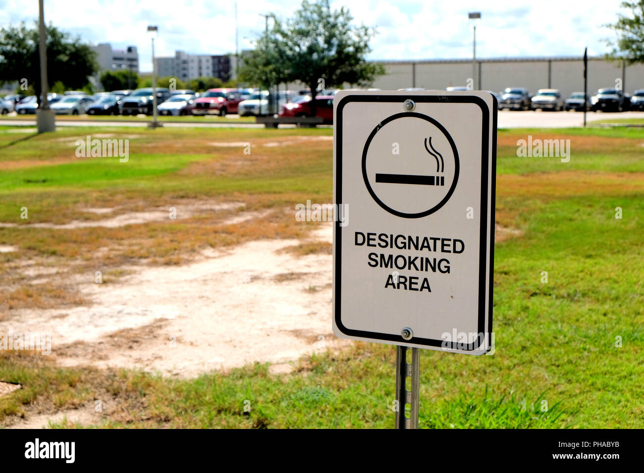 Designated Smoking Area sign outside with parking lot in background