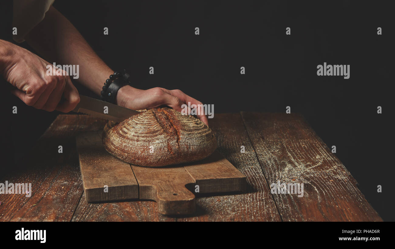 Men's hands cut bread Stock Photo