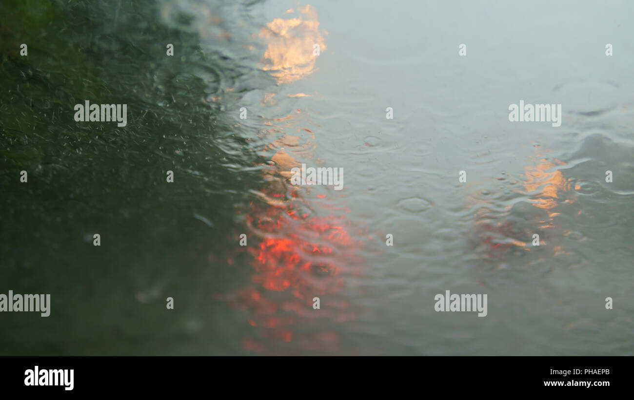 Road view through car window with rain drops, Driving in rain. Window's car while heavy rain. Stock Photo