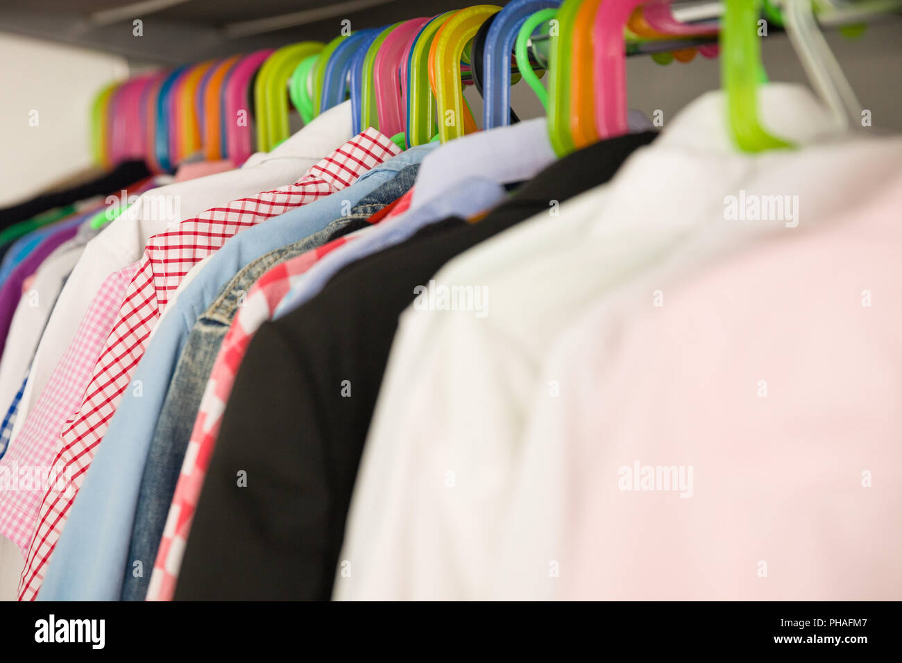 Children clothes on hangers in a room. wardrobe with boy's clothes on hangers. Shopping and consumerism concept. Dressing closet with clothes arranged Stock Photo