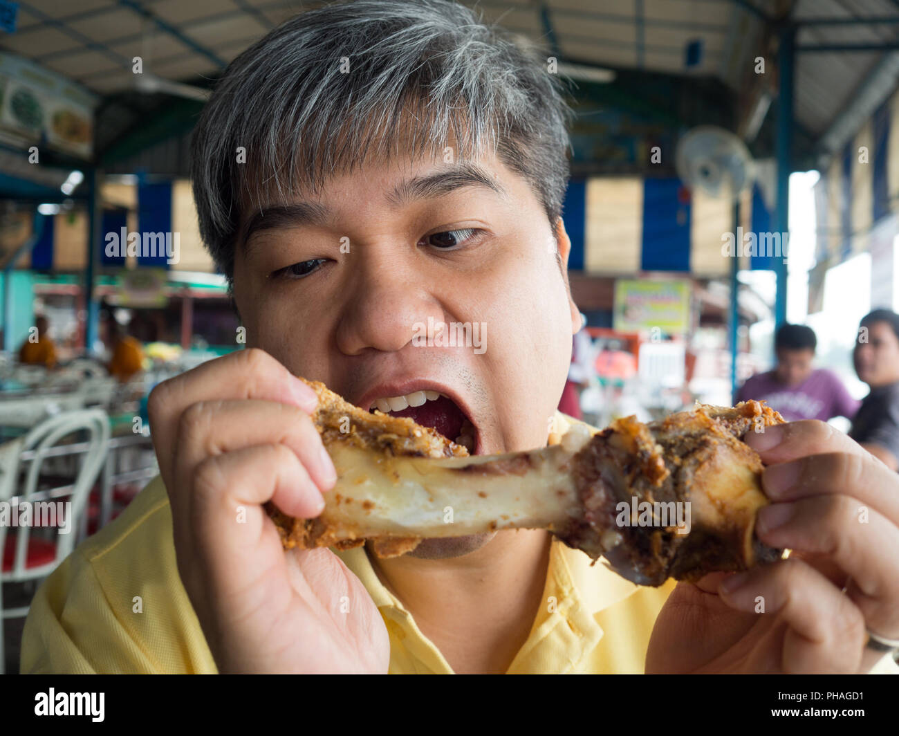 Asian man eating pork bone After eating the leg of crispy grilled pork